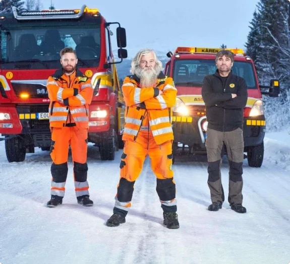 Personal från Årebärgarn uppställda framför sina röda bärgningsbilar i ett snötäckt Åre.