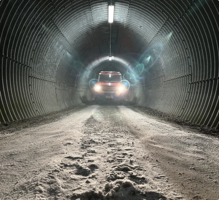 Ett utryckningsfordon eller bärgningsbil som kör genom en vintrig och snötäckt tunnel i Jämtland.