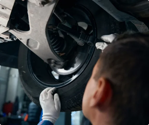 Arbete i en mekanisk verkstad eller plåtverkstad med reparation och kontroll under bilen.