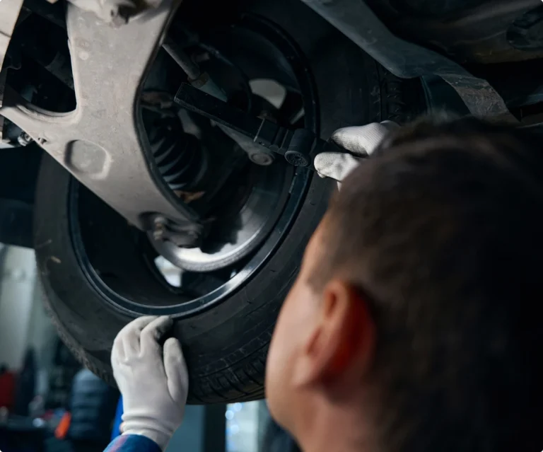 Arbete i en mekanisk verkstad eller plåtverkstad med reparation och kontroll under bilen.